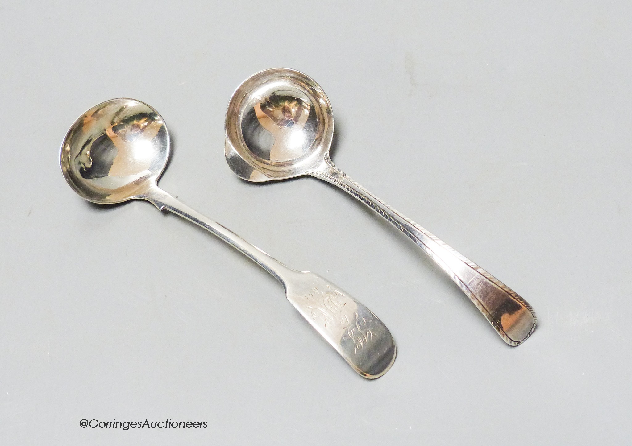 A small Georgian silver feather edge Old English pattern cream ladle by Hester Bateman, 10.9cm, together with a Victorian provincial silver fiddle pattern cream ladle.